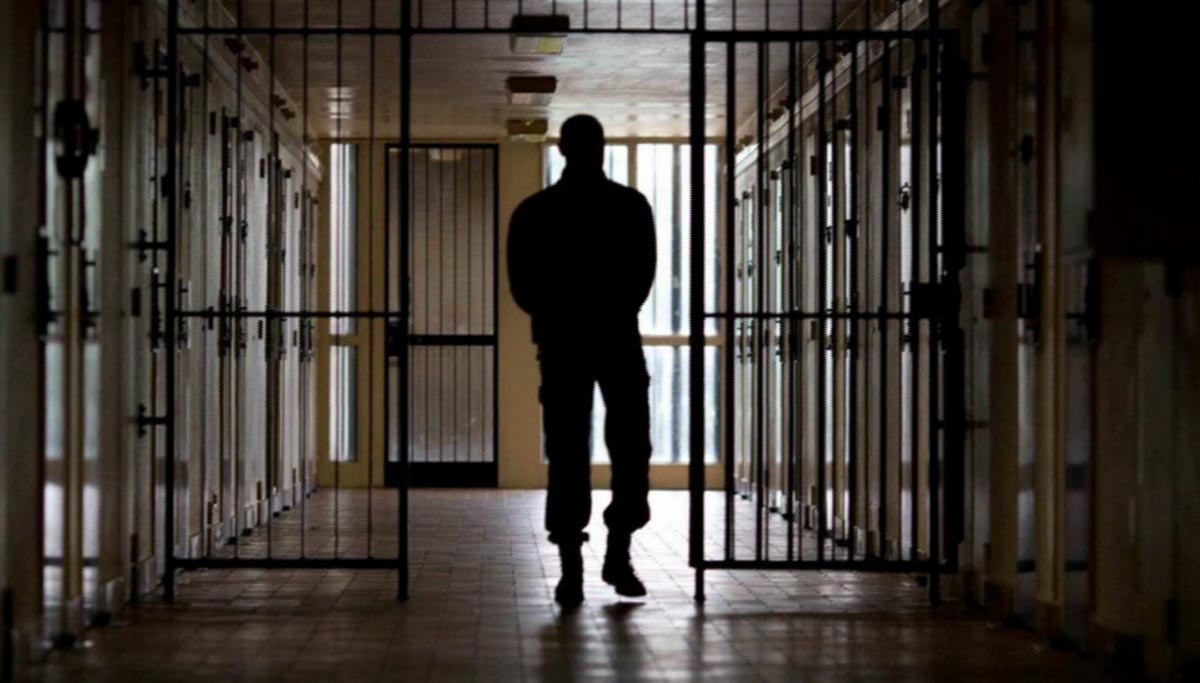 silhouette of jail inmate behind bars
